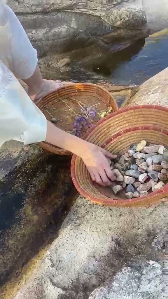 Mani che scelgono le pietre raccolte, dentro un cesto di vimini